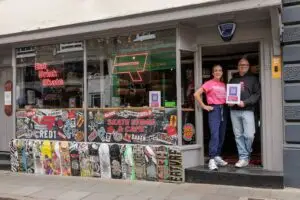 Kerry with the owner of RED1 Skate Store and Cafe in Hitchin holding the Refuge QR code poster